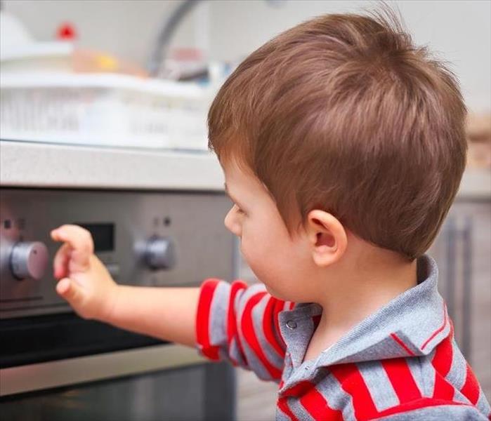 young boy attempting to touch the stove